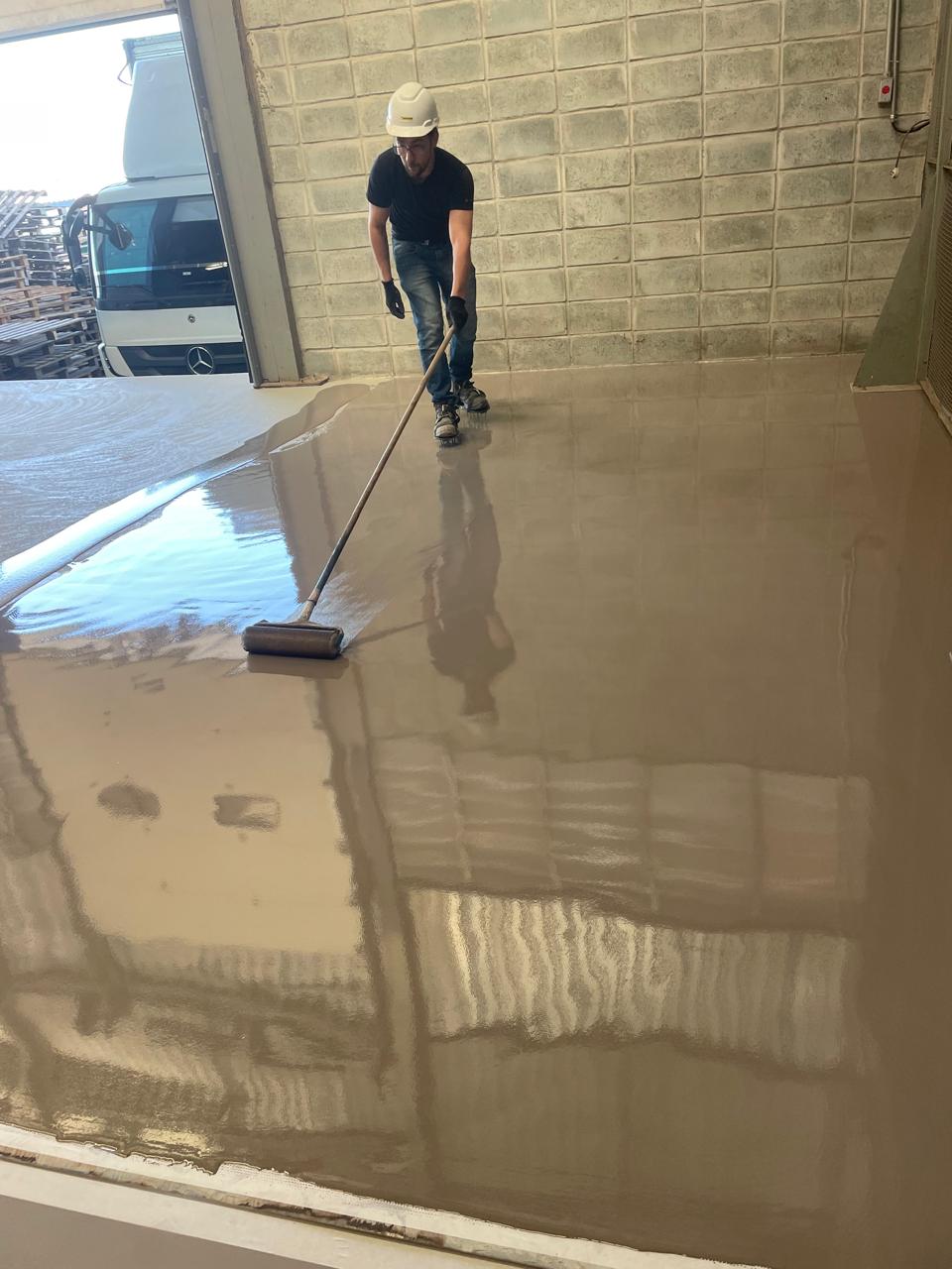 Profissional aplicando revestimento de uretano em piso industrial